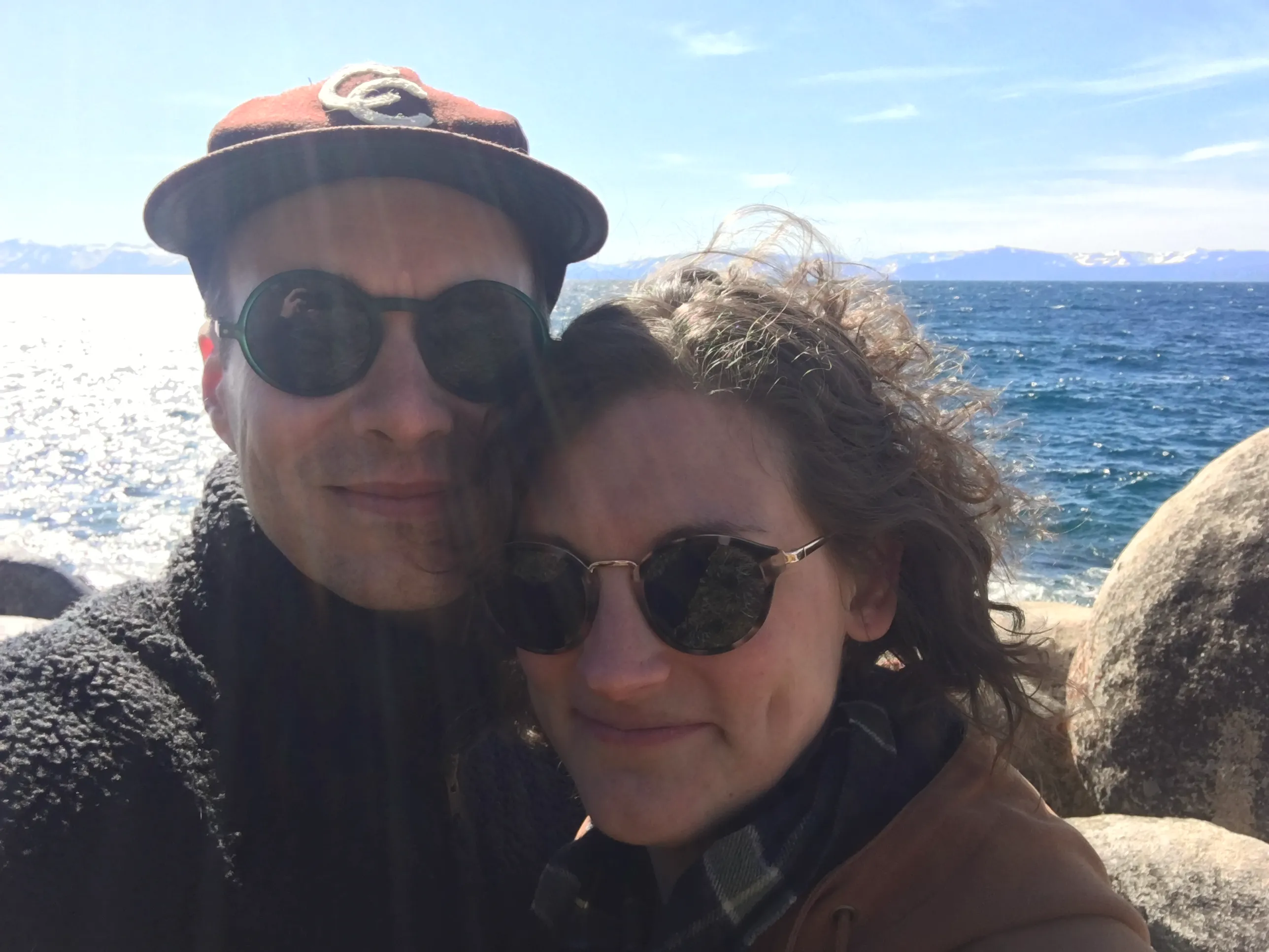 Two people standing in front of Lake Tahoe in the winter.